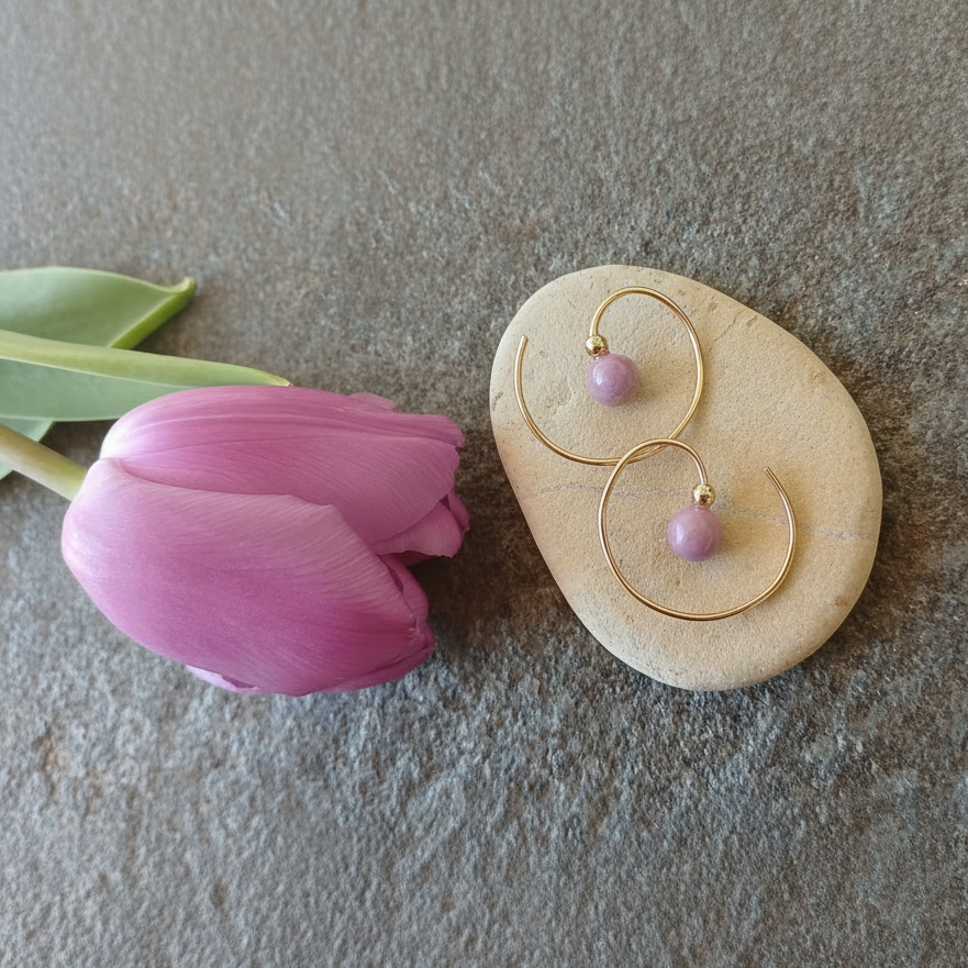 een tulp in een lenteachtige lila kleur met gouden oorringen in spiraalvorm met een lichtpaars steentje van fosfosideriet en een goud bolletje erboven. 