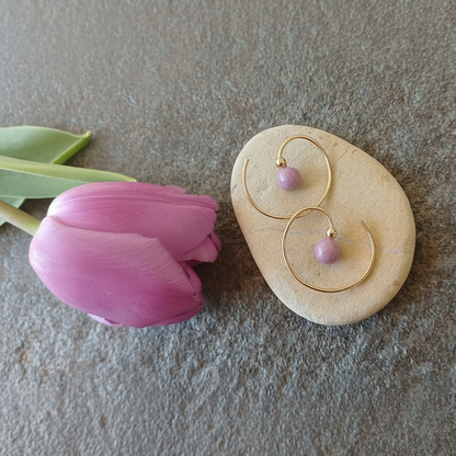 een tulp in een lenteachtige lila kleur met gouden oorringen in spiraalvorm met een lichtpaars steentje van fosfosideriet en een goud bolletje erboven. 